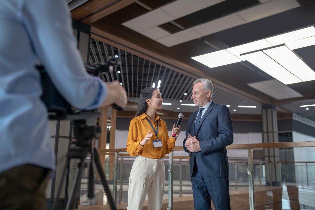 Asian female reporter asking questions to grey-haired man